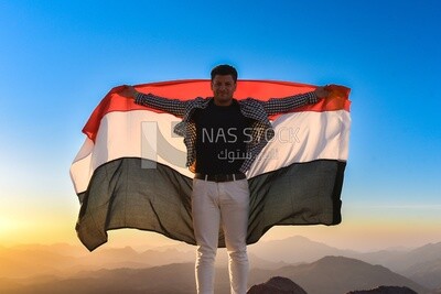 Man raises the Egyptian flag over the top of a mountain