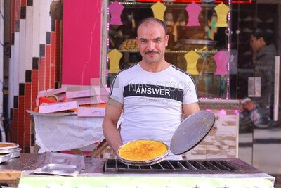 Man standing in the street selling konafa, Cart street, Ramadan vibes