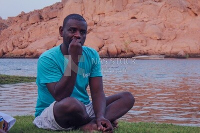 Nubian man sits on the shore of the Nile River in Aswan, Egypt