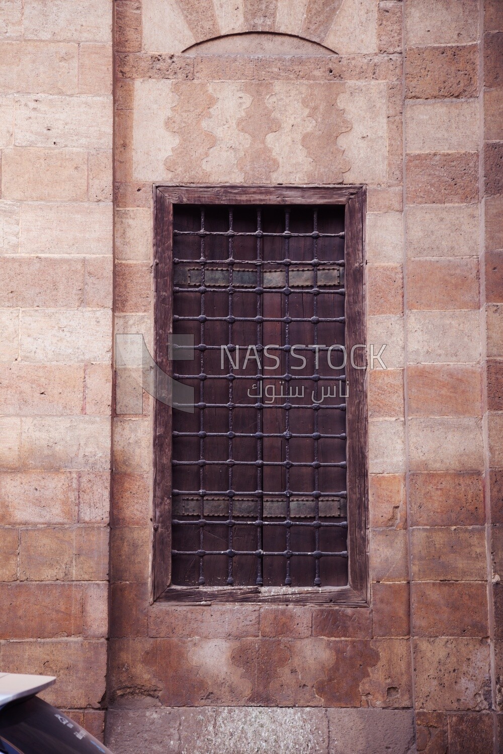 Grunge wooden aged window with iron bars on exterior stone bricks wall ,  Cairo, Egypt