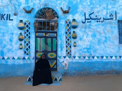 Nubian woman sits in front of her colorful house , Aswan,Egypt