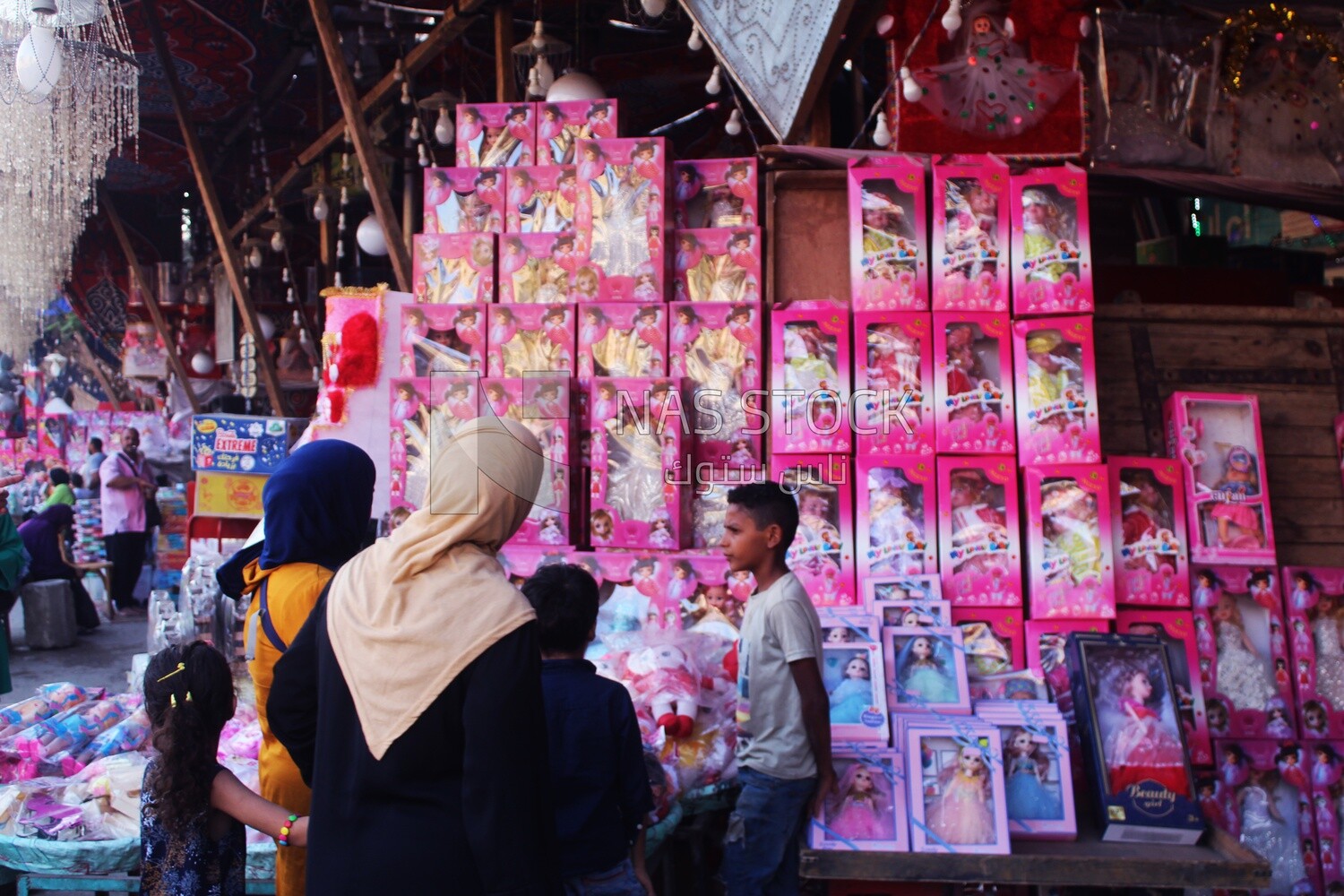 Woman with her children standing buying the Mawlid dolls in the street, Egyptian Desserts of Prophet Muhammad&#39;s Birth Celebration