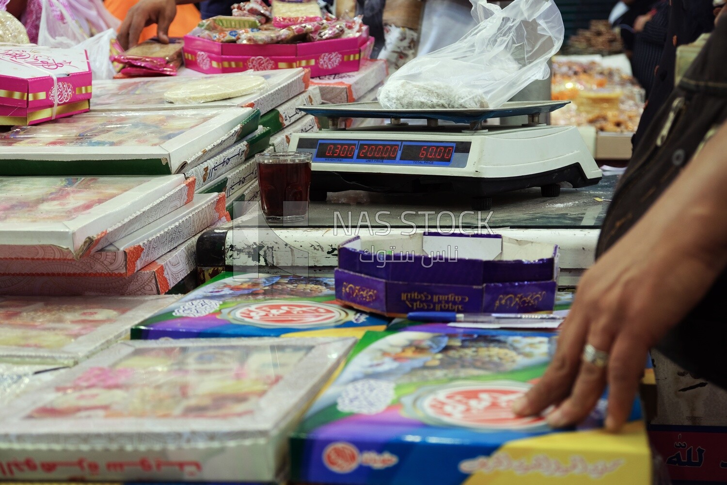 Man stands and places the candies of Prophet Muhammad&#39;s Birth on a scale
