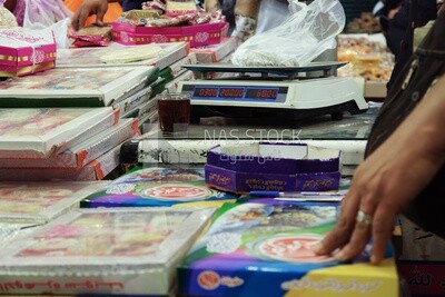 Man stands and places the candies of Prophet Muhammad&#39;s Birth on a scale