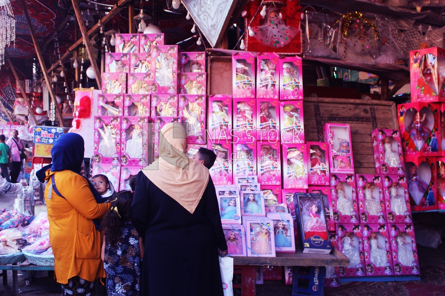 Woman with her children standing buying the Mawlid dolls in the street, Egyptian Desserts of Prophet Muhammad&#39;s Birth Celebration