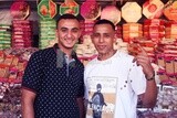 Close up of two men standing in front of a place selling the candies of the prophet Muhammad&#39;s birth