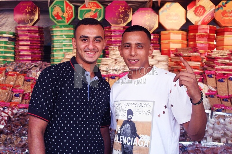 Close up of two men standing in front of a place selling the candies of the prophet Muhammad&#39;s birth