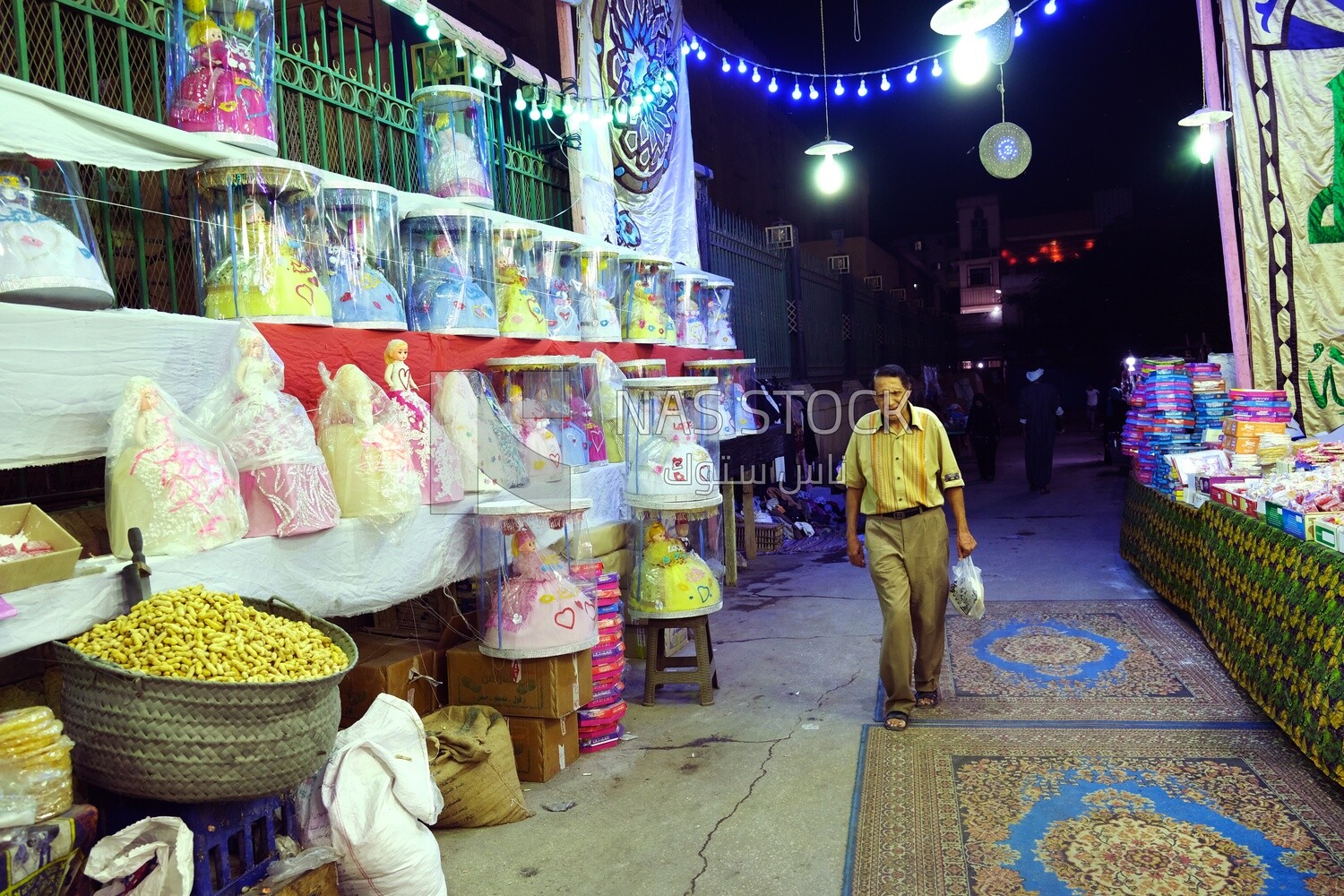 Man walking in the path beside the candies of Prophet Muhammad&#39;s Birth Celebration and the Mawlid dolls