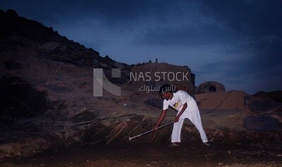 Young Nubian man digs the ground with an ax