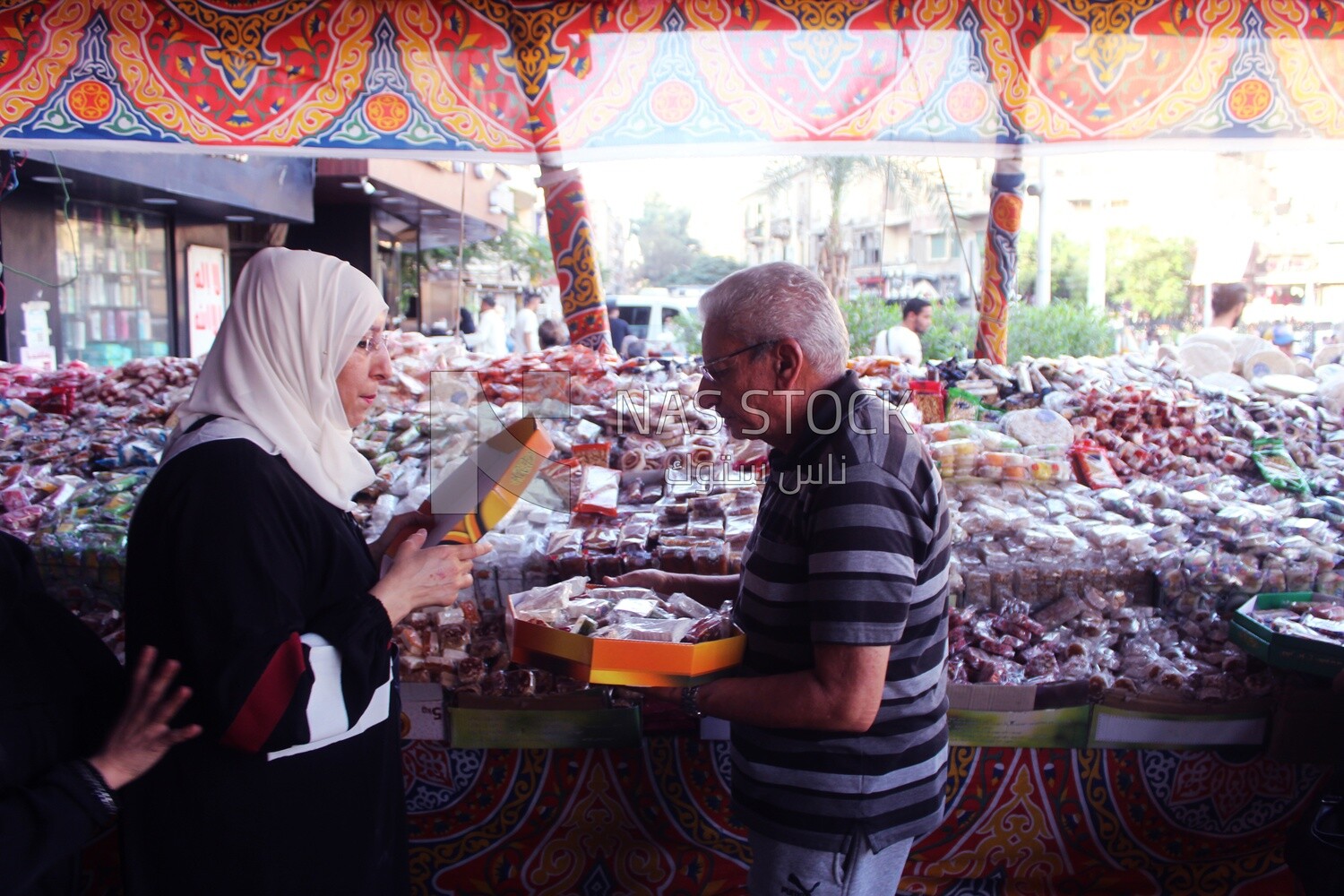 Man helps a woman buy the candies of the prophet Muhammad&#39;s birth on the street