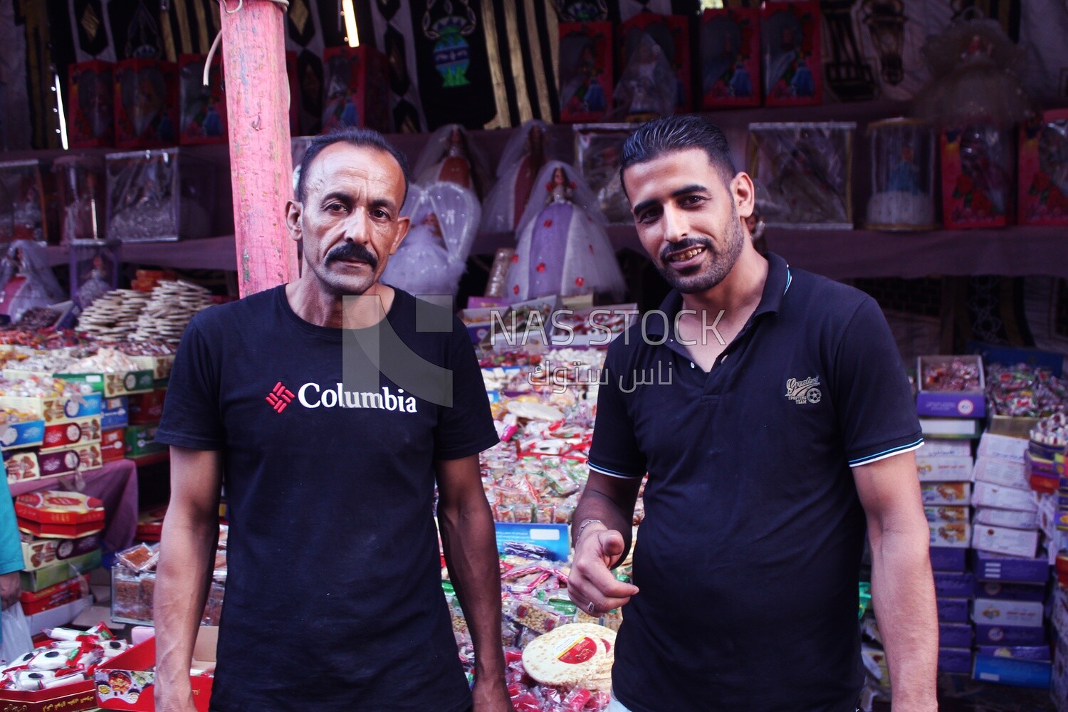 Close up of two men standing in front of a place selling the candies of the prophet Muhammad&#39;s birth