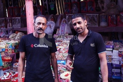 Close up of two men standing in front of a place selling the candies of the prophet Muhammad&#39;s birth