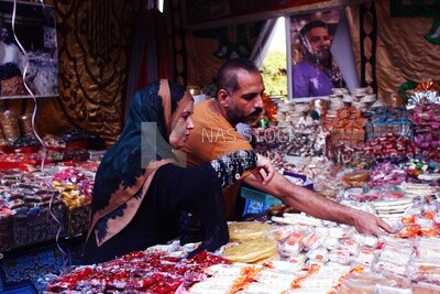 Man helps a woman buy the candies of the prophet Muhammad&#39;s birth on the street