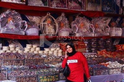 Woman talking on the phone while she buys the candies of the prophet Muhammad&#39;s birth on the box