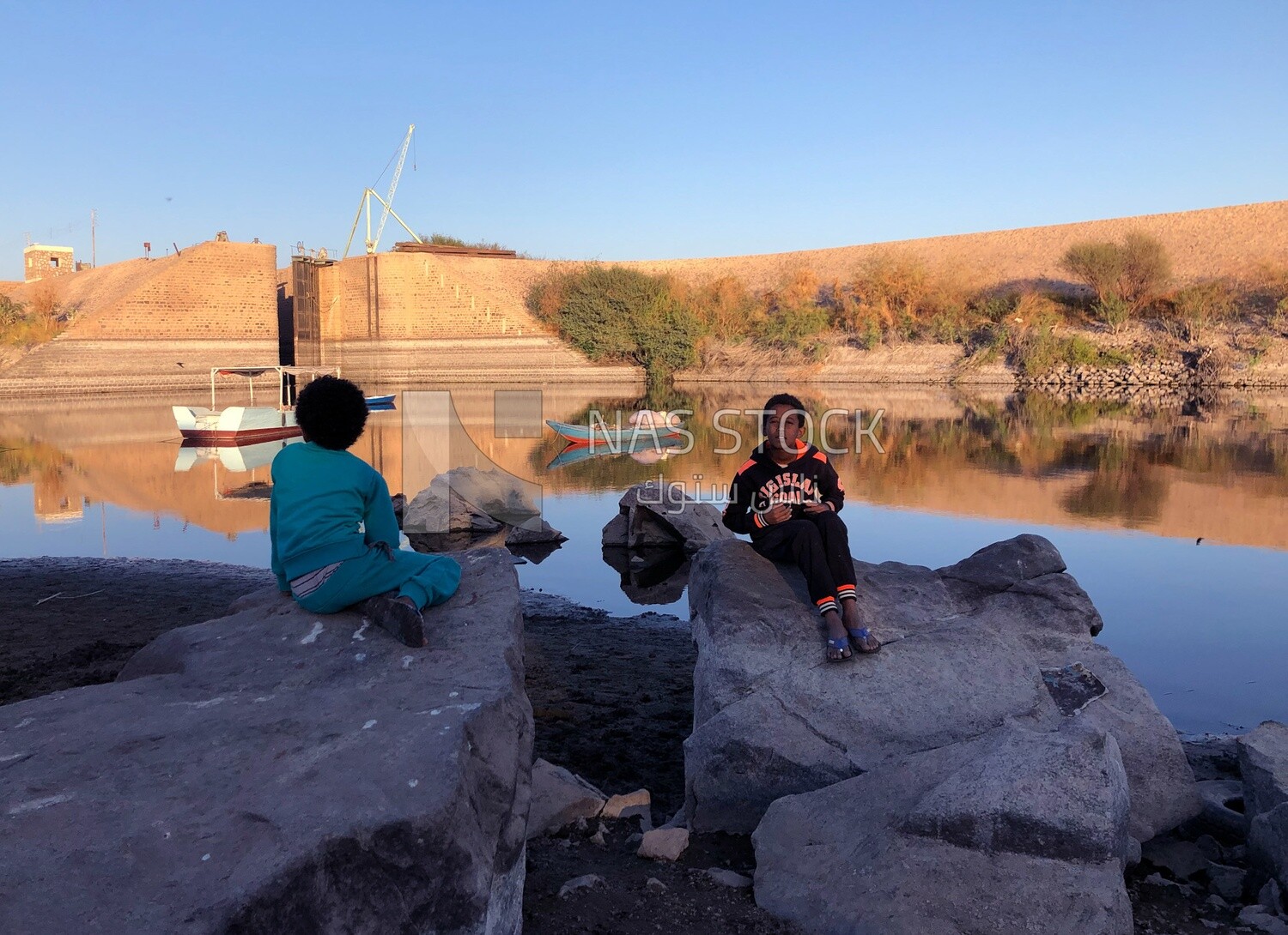 Two Nubian children sitting on the bank of the Nile River ,Aswan, Egypt
