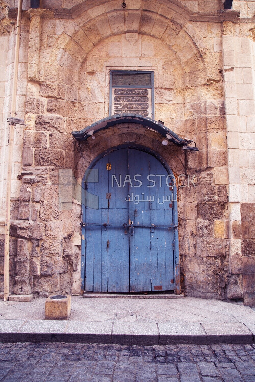 Old blue wooden double door in an ancient authentic stone wall , Stone medieval buildings