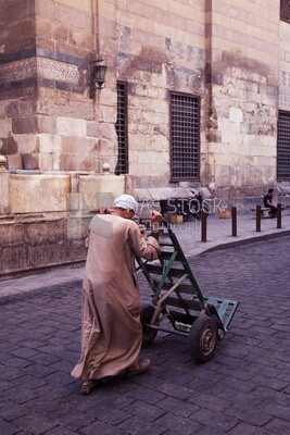 Egyptian worker pulls an iron cart to transport goods on Al Moez Street, Cairo, Egypt