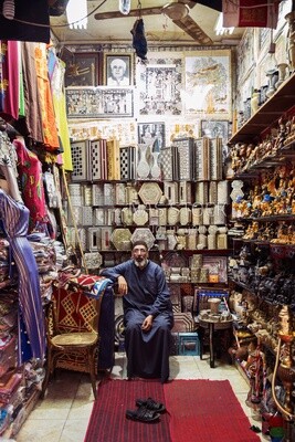 Man sits in a shop that sells souvenirs and gifts on Al-Moez Street