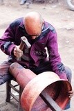 Man carrying a hammer works on aluminum vessels, Ahmed Al-Badawi