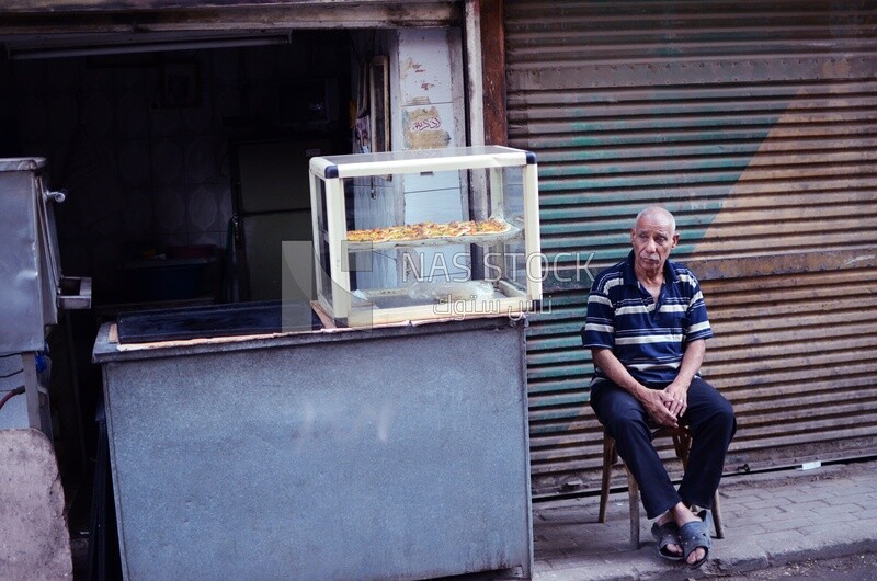Man sits next to his shop
