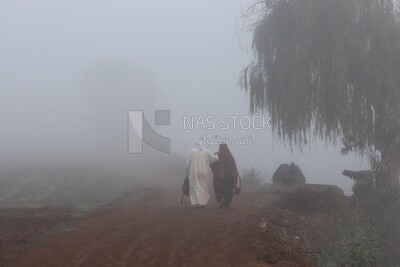 Man and Egyptian women walking in the street on a foggy day
