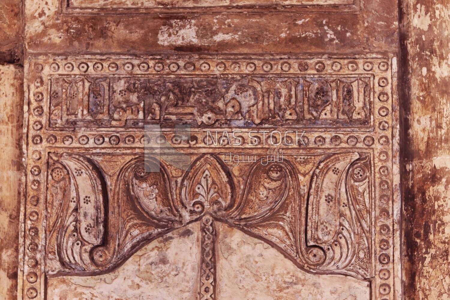 The wall of Ibn Tulun Mosque is Ornate engraved stone with floral patterns and calligraphy
