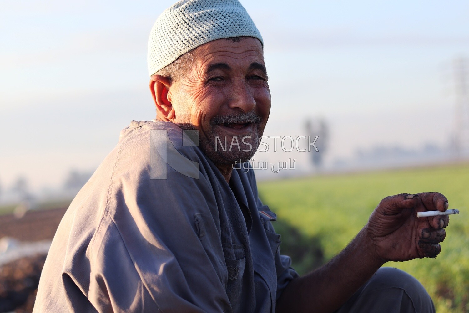 Farmer sitting in the field smoking taking a break from alfalfa cultivation