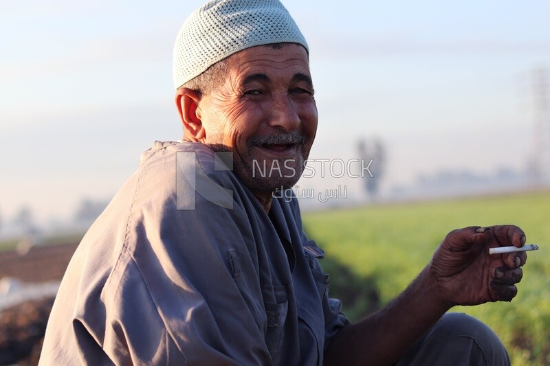 Farmer sitting in the field smoking taking a break from alfalfa cultivation