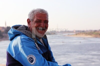 Close up of an old man sitting in front of the river