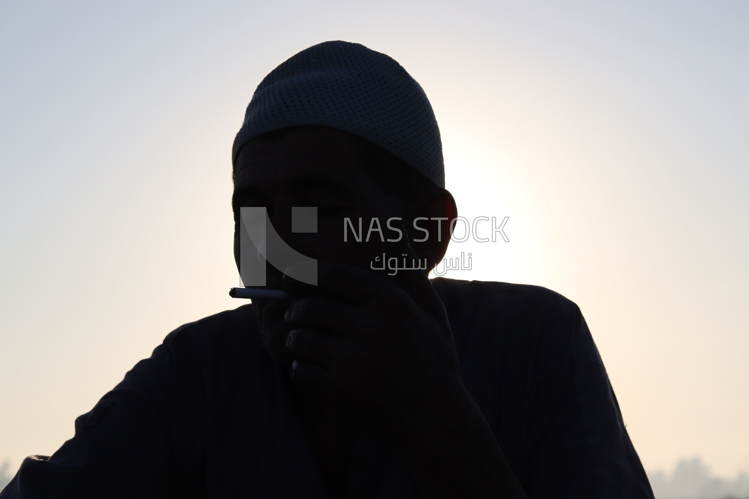 Farmer sitting in the field smoking taking a break from alfalfa cultivation
