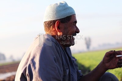 Farmer sitting in the field smoking taking a break from alfalfa cultivation