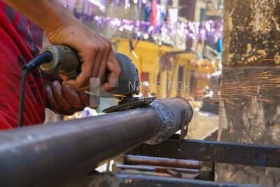 Worker cutting metal with a grinder in his workshop, the fire Sparks while grinding the iron