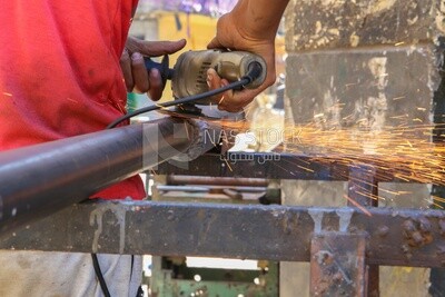 Worker cutting metal with a grinder in his workshop, the fire Sparks while grinding the iron