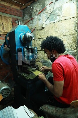 Young man works on a machine in a workshop
