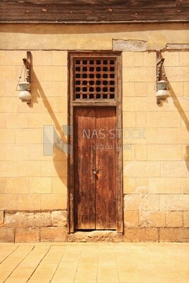 Wooden closed door and two Arabic glass street lanterns hung on a wooden pole, The School and dome of Sultan Al-Nasir Qalawun