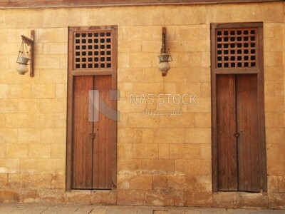 Wooden closed door and two Arabic glass street lanterns hung on a wooden pole, The School and dome of Sultan Al-Nasir Qalawun