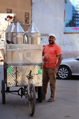 Man standing by a Portable mouthwatering tamarind juice Cart, Sale on the street