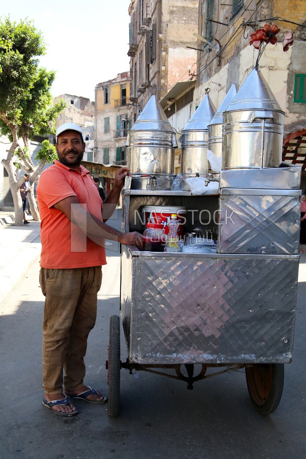 Man standing by a Portable mouthwatering tamarind juice Cart, Sale on the street