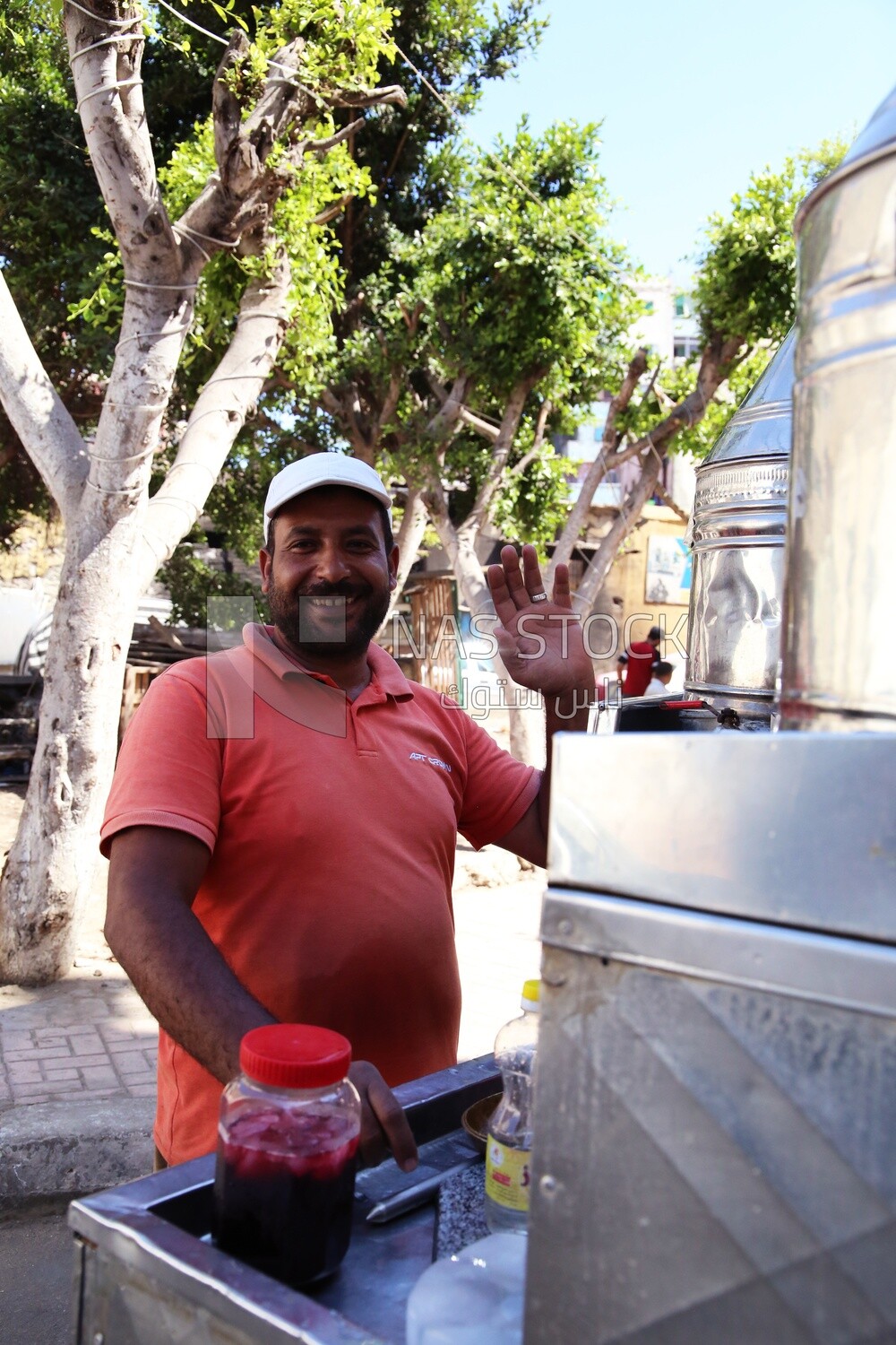 Man standing by a Portable mouthwatering tamarind juice Cart, Sale on the street