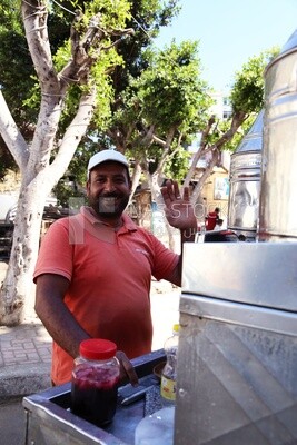 Man standing by a Portable mouthwatering tamarind juice Cart, Sale on the street