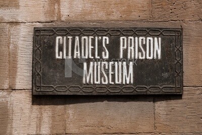 Hanging sign with the name of the citadel&#39;s prison museum on the wall