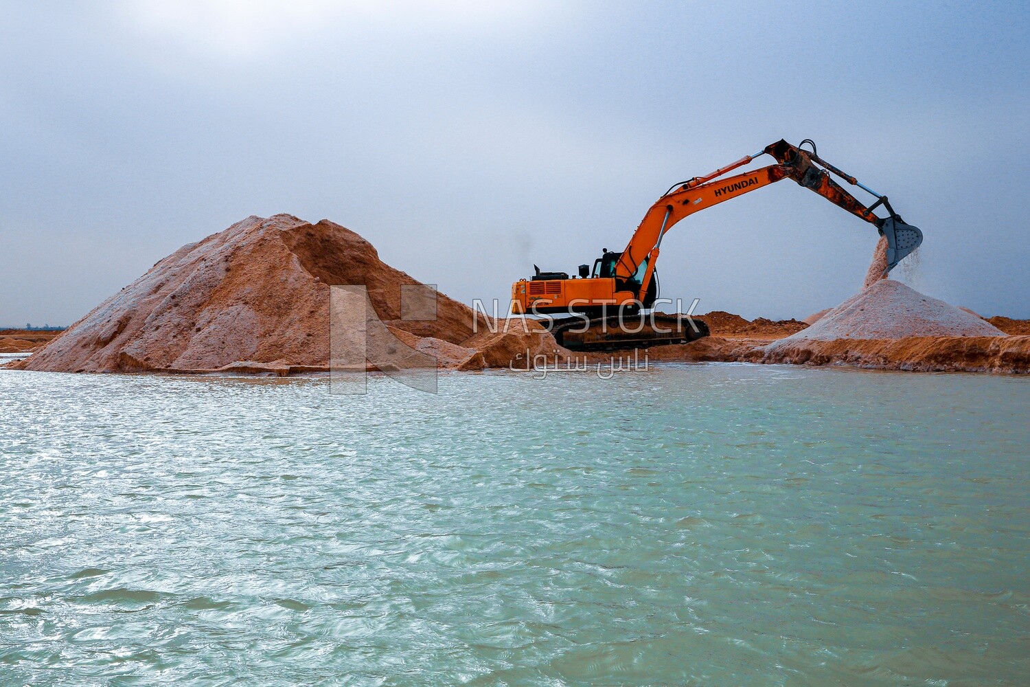Excavator shoveling salt, salt production of a saline