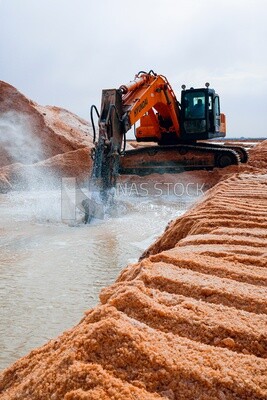 Excavator shoveling salt, salt production of a saline
