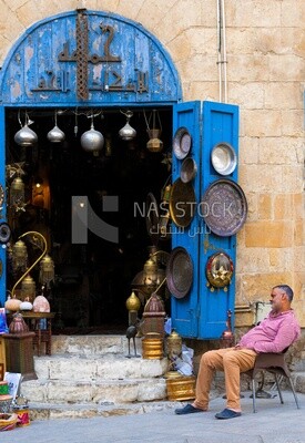 رجل يجلس أمام محل لبيع الهدايا التذكارية في المعز لدين الله في القاهرة الفاطمية