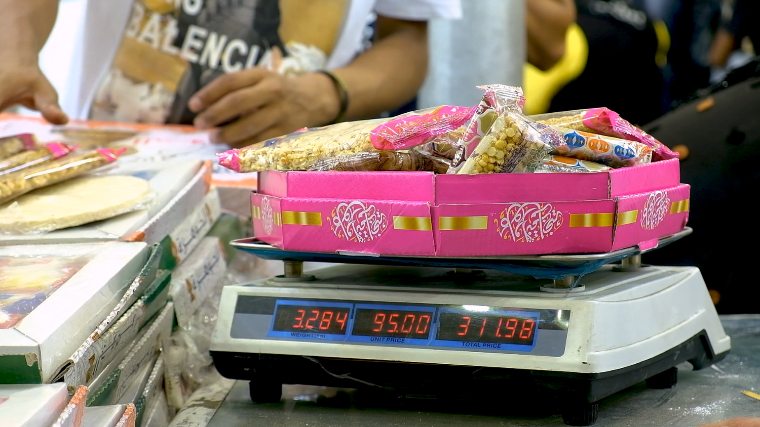 Man stands and places the candies of Prophet Muhammad&#39;s Birth on a scale