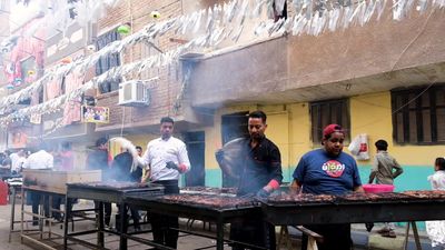 Men standing in front of the grill cooking, Ramadan Kareem, preparing their iftar