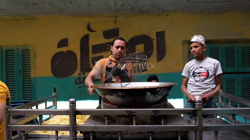 Man standing frying potatoes, Ramadan Kareem, preparing breakfast