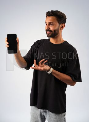 صورة امامية شاب ملتحى يرفع هاتفه امام الكاميرا , اعلانات التطبيقات