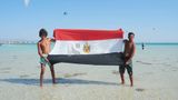 Two young men raise the flag of Egypt on one of the beaches