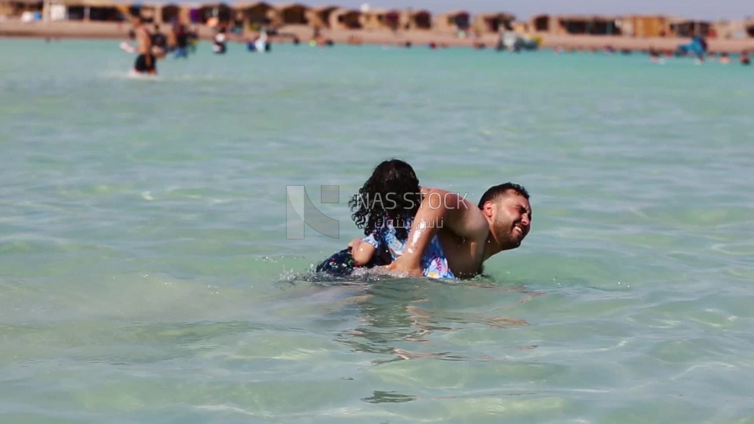 Little girl enjoying learning to swim with her father in the sea and fresh air